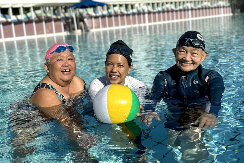 Senior collaborators, Yim Fong, Michelle, Tong Cheng, holding a beach ball in the swimming pool